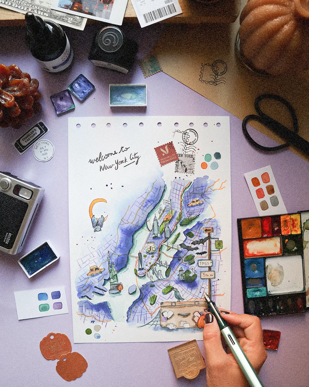 Carte de New York à l'aquarelle sur le bureau de l'illustratrice, entre aquarelles et citrouilles